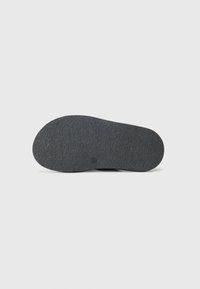 Black rubber shoe sole with a textured surface, featuring a rounded shape and a smooth edge, suitable for various shoe designs.