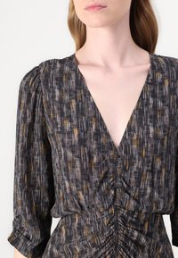 Schwarz gemustertes Kleid mit tiefem V-Ausschnitt, gerafftem Bund und Dreiviertelärmeln. Verfügt über subtile goldene und weiße Streifen. Leichter Stoff.
