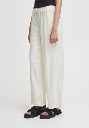 Lichte, wijde broek in een zachte beige stof met een elastische tailleband en trekkoord. Gepaard met zwarte, chunky sandalen.