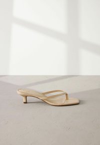 Sandales à talons nues avec un bout carré. Fabriquées en matériau lisse, avec des fines lanières qui croisent le pied et un petit talon bloc.