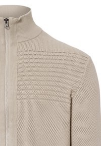 Maglione zip-up beige chiaro con un design a maglia testurizzata, caratterizzato da un colletto a coste e pannelli a contrasto sulle spalle.