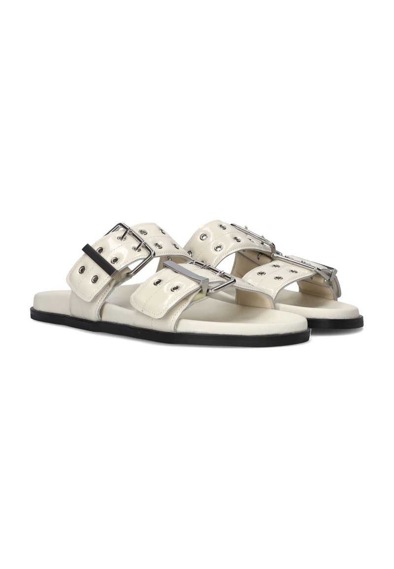 Witte leren sandalen met twee brede banden voorzien van zilveren gespen en oogjes, flatte zwarte zolen en een minimalistisch ontwerp.