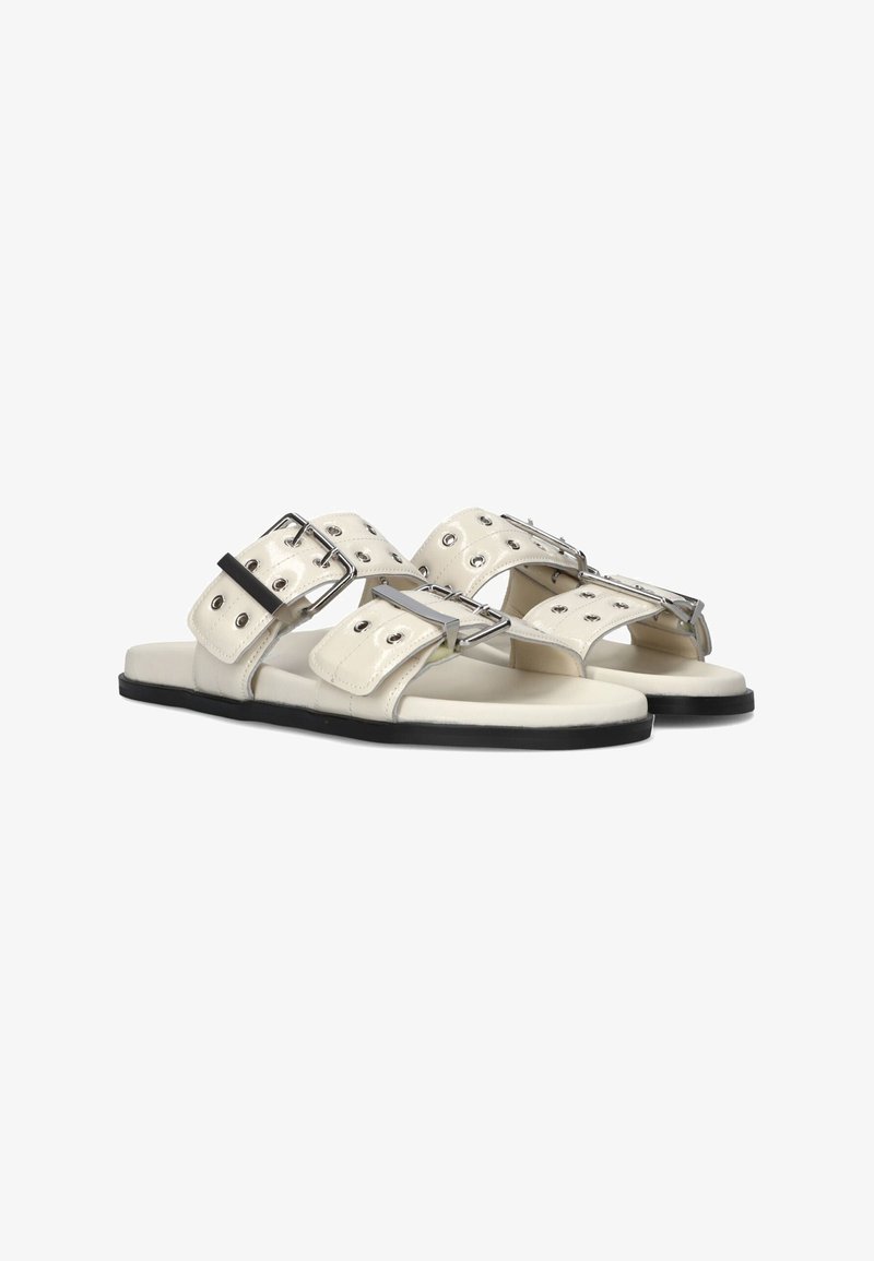 Witte leren sandalen met twee brede banden voorzien van zilveren gespen en oogjes, flatte zwarte zolen en een minimalistisch ontwerp.