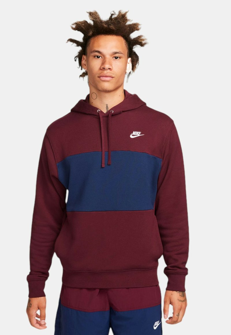 Felpa con cappuccio a blocchi di colore maroon e navy, con vestibilità aderente, cappuccio con cordino e logo Nike sul petto. Tessuto morbido con polsini a costine.