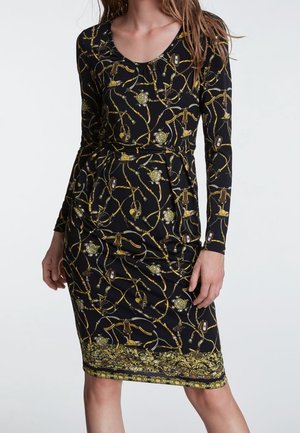 Czarna sukienka z długim rękawem, zdobiona złoto-zielonym wzorem łańcuchów i kwiatów, z dopasowanym krojem i okrągłym dekoltem.