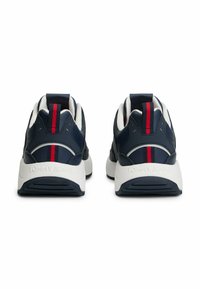 Granatowe sneakersy z białymi akcentami, z czerwonym paskiem na pięcie, teksturowanym materiałem, wyściełanym kołnierzem i gumową podeszwą.