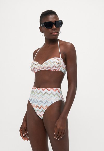 High-waisted bikini with a zigzag pattern in pastel colors, featuring a strapless top and halter neck. Made from smooth fabric.