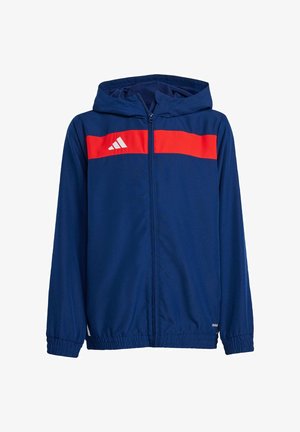 Marineblå zip-up hættejakke med en rød vandret stribe og hvid Adidas-logo på brystet. Har elastiske manchetter og en blød stofstruktur.