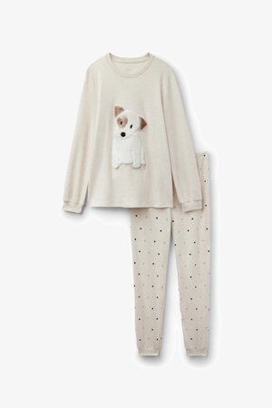 Beiges Langarmshirt mit einem flauschigen Hunde-Applikation; dazu passende Leggings mit kleinen schwarzen Herzen auf hellem Hintergrund. Weicher Stoff überall.