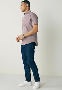 Kortærmet ternet skjorte i rød og hvid med klassisk krave. Sættes sammen med mørkeblå jeans og hvide sneakers.