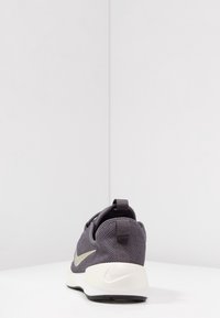 Nike sneakers med ett grått nätöverdrag, vit gummisula, kontrasterande logodetalj och en dragflik för enkel påtagning.