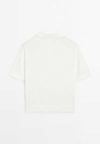 Lyhythihainen poolopaita valkoisena, valmistettu pehmeästä neulekudoksesta. Ominaisuuksiin kuuluu klassinen kaulus ja ribbaudet hihansuihin, sekä saumatonta selkädesignia.