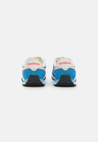 Sneakers din suede albastru cu un brâu alb. Au accente roz, o talpă texturată neagră și branding "Reebok" pe călcâi.
