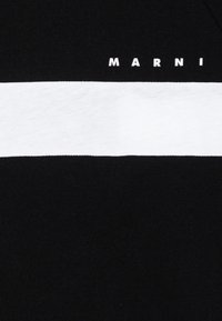 Svart och vit t-shirt av bomull, med ett horisontellt vitt streck över mitten och varumärket "MARNI" i vita bokstäver.