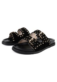 Svarta mockaskor med två breda remmar som har guldöglor och spännen, på en platt svart gummisula. Slät innerskikt.