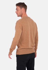 Pull en marron clair, en maille, col rond, avec des poignets et un ourlet côtelés, présentant une texture lisse et une coupe décontractée. Vue de dos présentée.