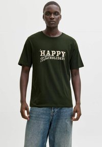 Tumed roheline puuvillane T-särk, millel on valged kirjad "ÕNNE ja Häid Jõulupühi." Klassikaline ümmargune kaelus ja mugav lõige.