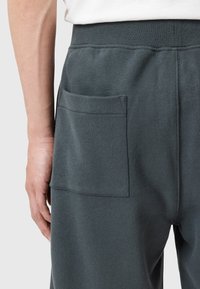 Donkergrijze sweatpants van een zachte, getextureerde stof. Voorzien van een grote achterzak en een elastische tailleband voor extra comfort.