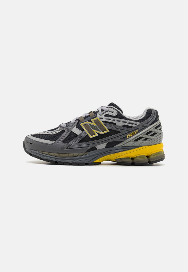 Chaussure de sport New Balance grise et noire avec des accents jaunes et une semelle rembourrée, vue de profil sur fond blanc.