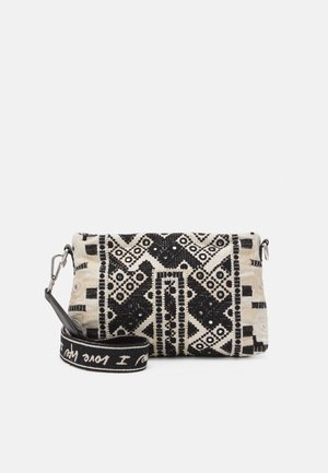 Sac à main à motifs noirs et crème avec des dessins géométriques, tissu texturé, fermeture éclair et bandoulière amovible avec un accent textuel.