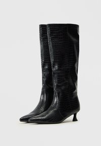 Botas negras hasta la rodilla, hechas de un material texturizado con estampado de cocodrilo, que cuentan con una punta afilada y un pequeño tacón afilado.