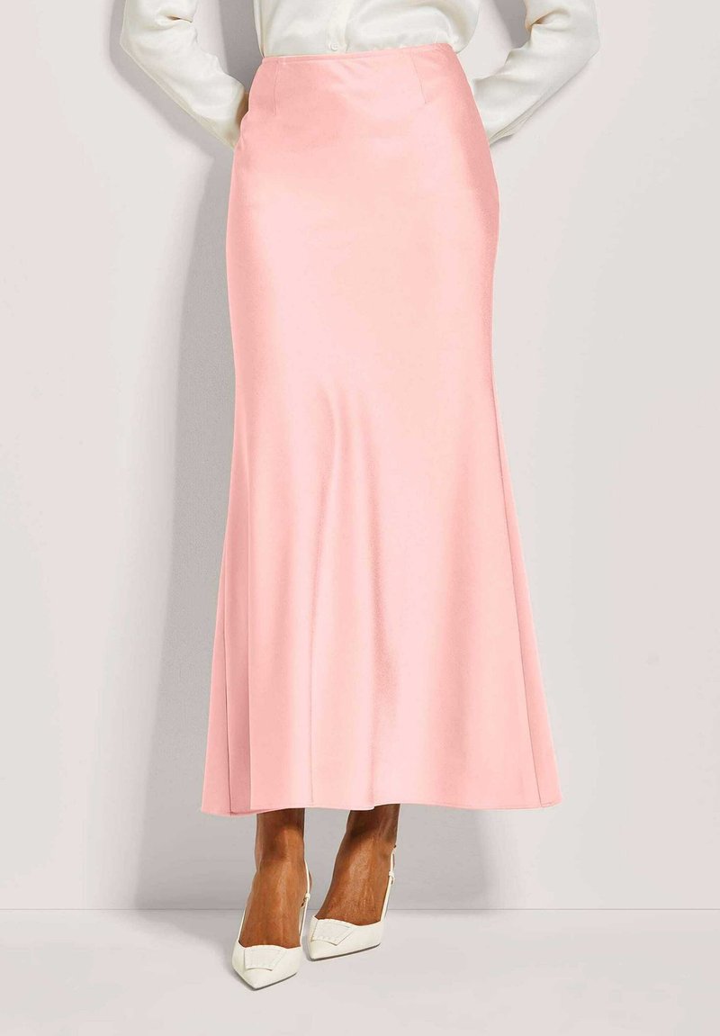 Roze satijnen maxi rok met een uitlopende silhouet, voorzien van een gladde textuur en een tailleband. Gepaard met witte hoge hakken.