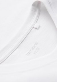 Gros plan sur l'encolure d'un T-shirt blanc en coton montrant l'étiquette intérieure imprimée avec la marque et la taille M/40.