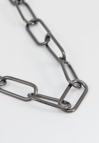 Chaîne en métal de couleur gris foncé avec des maillons rectangulaires allongés et une texture lisse, entrelacés pour une résistance et une durabilité accrues.