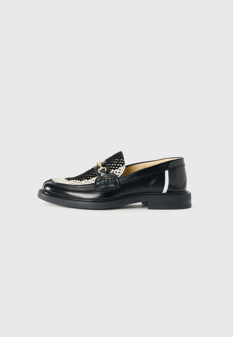 Loafers din piele alb-negru au un design împletit, vârf rotunjit, accesorii decorative din aur și o curea texturată neagră cu o talpă netedă.