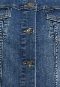 Džínová košile s předním zapínáním na knoflíky ve stříbrné barvě, kontrastním prošitím a klasickým modrým vypráním.