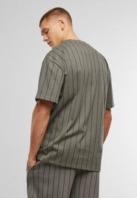 Camiseta de manga corta a rayas verdes, fabricada con una mezcla de algodón, que presenta un corte relajado, escote redondo y detalle en las costuras laterales.