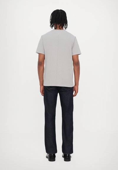 Gray short-sleeve t-shirt with a straight cut and a back seam, paired with dark blue denim jeans and black shoes. Minimalist design.