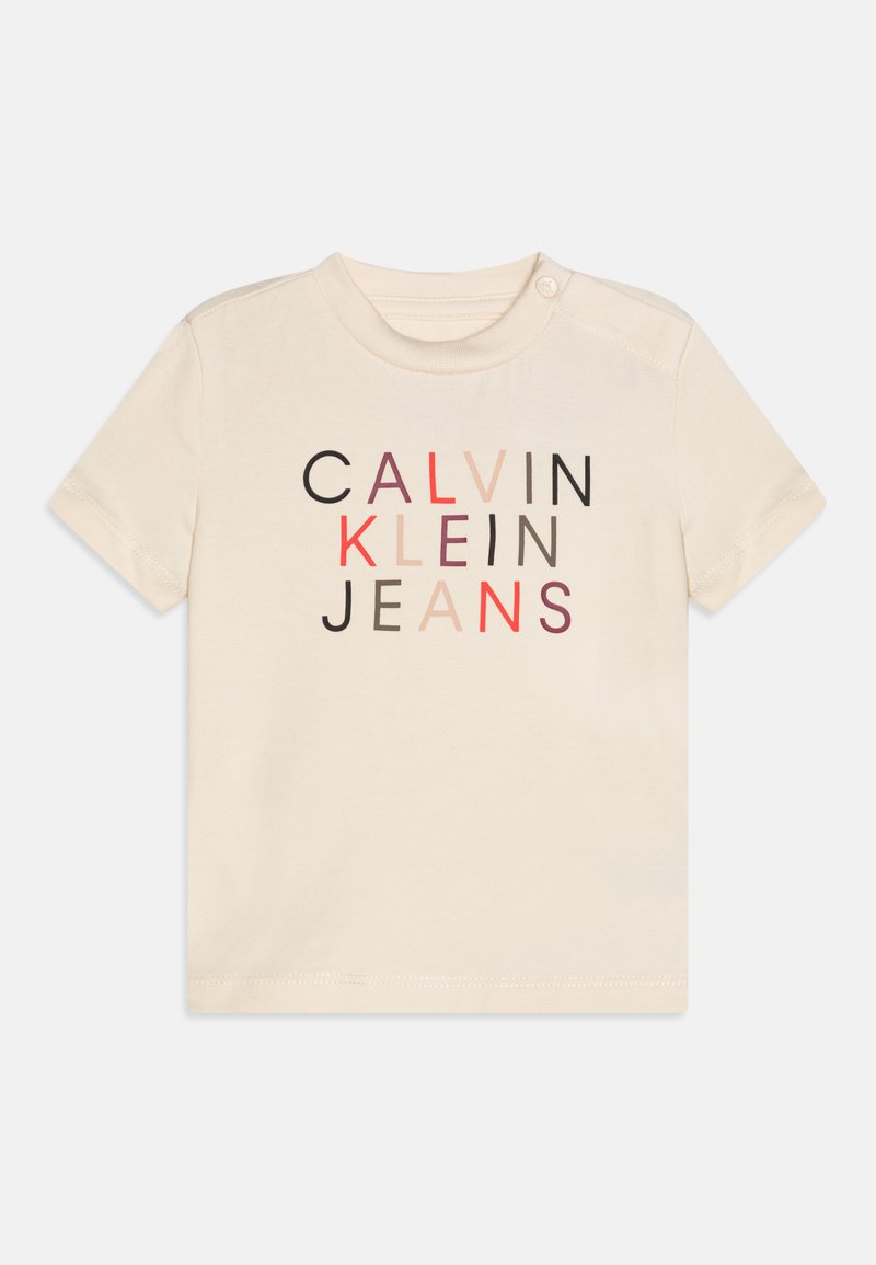 Kokvilnas t-krekls ar īsām piedurknēm krēmkrāsā, ar daudzkrāsainu grafisko drukājumu "CALVIN KLEIN JEANS" ar dažādiem fontu svara un krāsu variantiem.