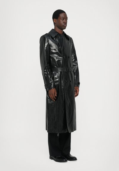 Trench coat negro y brillante hecho de material brillante, que cuenta con un cinturón, diseño de doble botonadura y un cuello clásico.