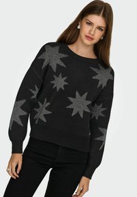 Czarny sweter z wzorem srebrnych gwiazdek, okrągły dekolt, długie rękawy i ściągacz u dołu. Miękki materiał, luźny kroj, idealny na codzienne wyjścia.