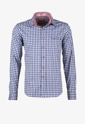 Homme portant un lederhosen traditionnel en cuir marron avec des bretelles brodées, une chemise à carreaux bleue, des chaussettes montantes et des chaussures marron.