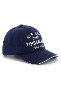 Sötétkék pamut baseball sapka fehér "TIMBERLAND EST 1973" felirattal. Ívelt csúcs, állítható pánt és kontrasztos fehér varrási részletek.
