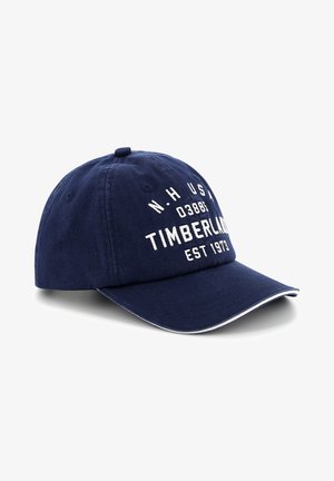 Granatowa bawełniana czapka baseballowa z białym napisem "TIMBERLAND EST 1973." Z zakrzywionym daszkiem, regulowanym paskiem i kontrastującymi białymi szwami.