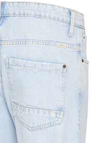 Jeans di denim azzurro chiaro con vita alta, tasca posteriore con cucitura a zigzag distintiva e una piccola etichetta del marchio vicino alla cintura.