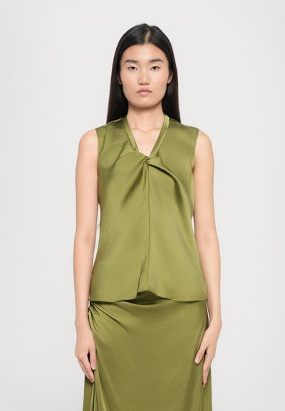 Haut sans manches vert olive avec un design noué à l'avant, texture satin lisse et ourlet légèrement évasé, associé à une jupe assortie.