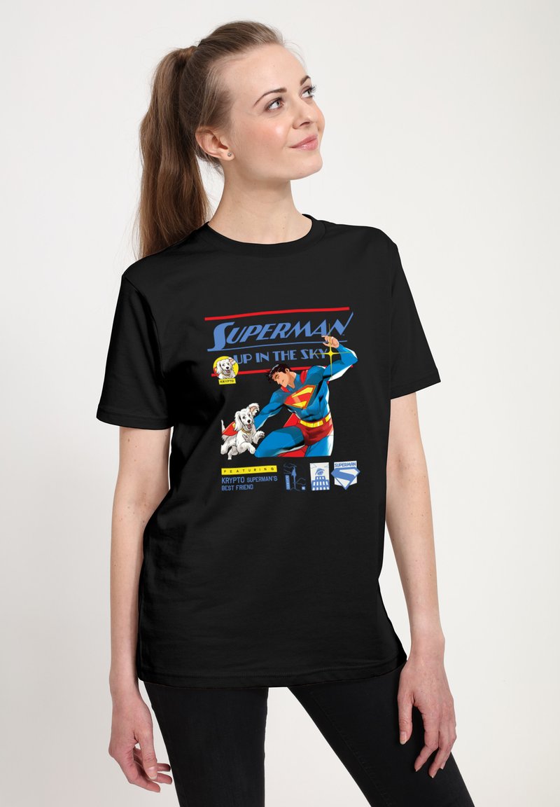 Černé bavlněné tričko s grafickým motivem Supermana s živými barvami, v komiksovém stylu, a textem "SUPERMAN NA NEBESÍCH" nahoře.