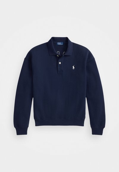 Temno modra polo majica s kapuco s klasičnim ovratnikom, tremi gumbi in vezenim logotipom na levem prsnem delu. Elastični manšeti in rob.