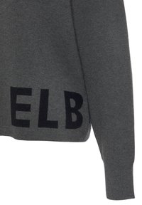 Grauer Pullover mit einem verkürzten Design, der auf einer Seite auffällige schwarze Buchstaben aufweist. Hergestellt aus strukturiertem Strickmaterial mit langen Ärmeln.