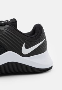 Zbliżenie czarno-białej pięty buta Nike z teksturowaną podeszwą i białym logo Nike swoosh po boku.