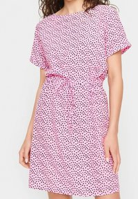 Rosa kortärmad klänning med knyt-midja, tillverkad av lättviktsmaterial med små svarta hjärtan i tryck.