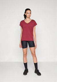 Tumepruun V-kaelusega T-särk lühikeste varrukatega, kombineeritud mustade põlveni ulatuvate lühikeste pükstega. Komplekti kuuluvad mustad sportlikud sokid ja jalanõud.