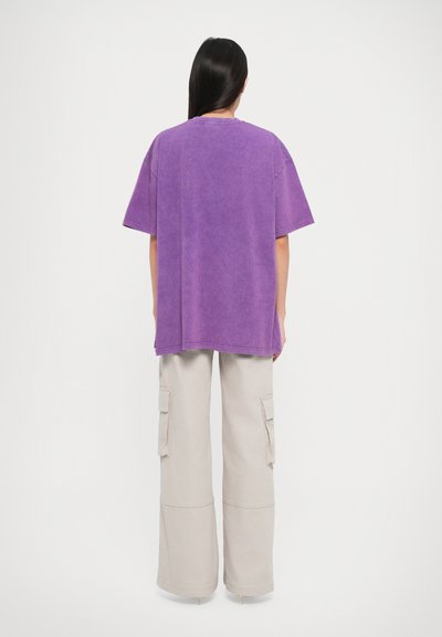 Lilla oversized t-skjorte med korte ermer, laget av myk stoff. Kombinert med lyse beige cargo-bukser med sidelommer.