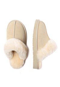 Beige Wildlederschuhe mit weichem Schaffellfutter, rückenlosem Design und strukturiertem Gummisohle. Mit sichtbaren Nähten und Logodetail.