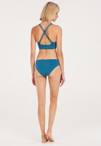 Blauwe bikini set met een crisscross-ontwerp op de rug en minimalistische onderkant. Glad textuur met een effen kleurafwerking.