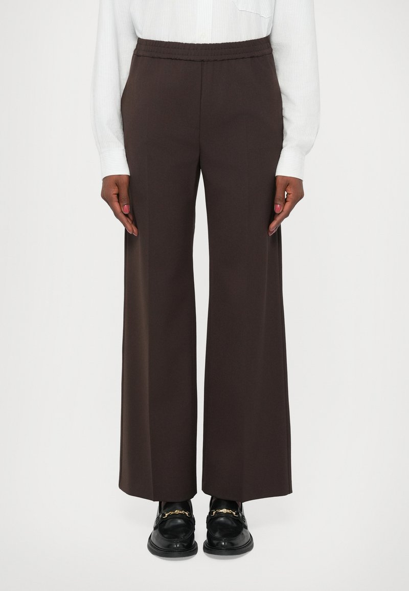 Pantaloni largi maro cu talie elastică, dintr-un material neted. Asortați cu loafers negri ce au accente de hardware aurie.